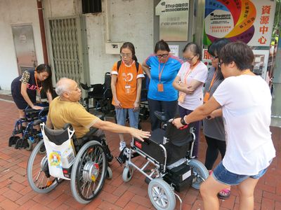 輪椅者、照顧者及義工一同商討如何加裝輪椅。